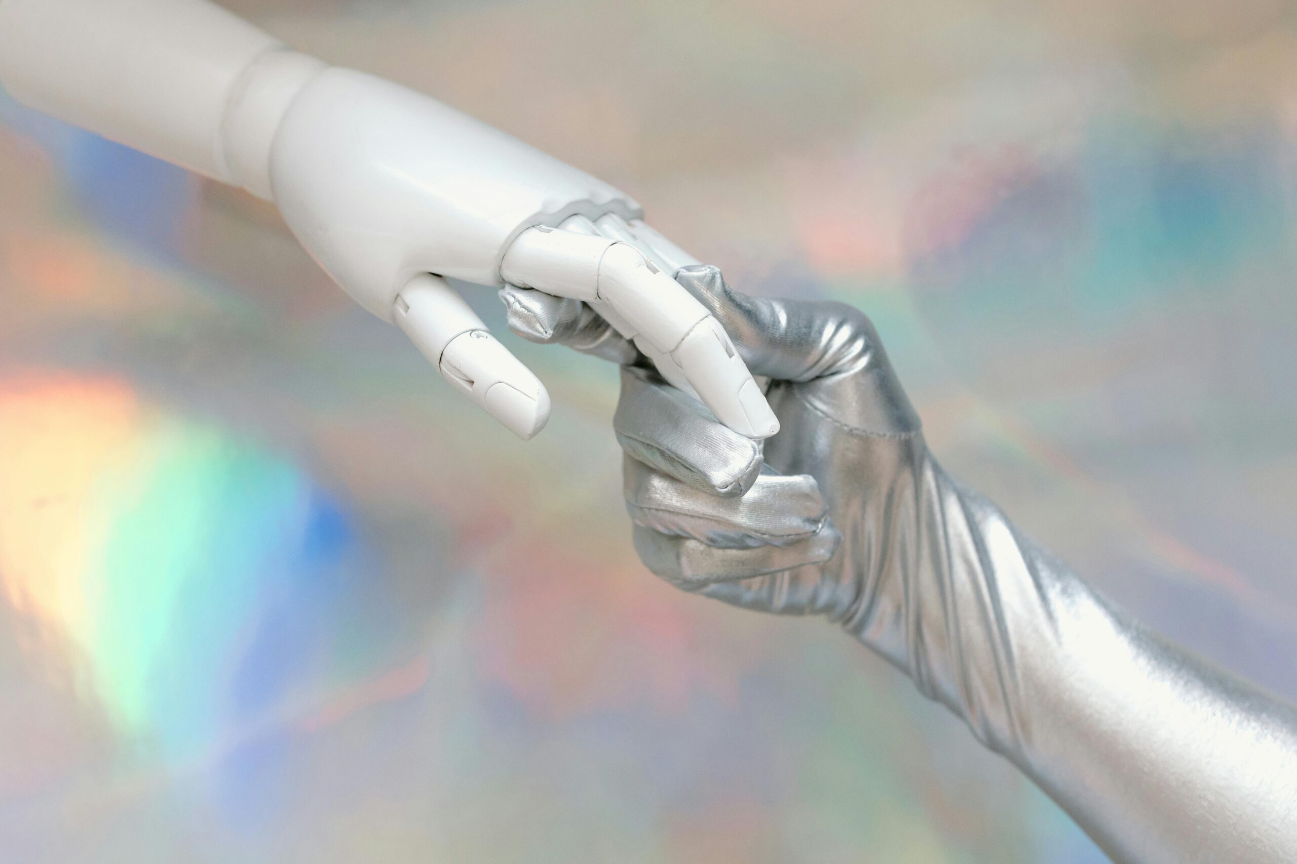 Home Close-up of a robot hand and silver-gloved hand touching, symbolizing human-robot connection.
